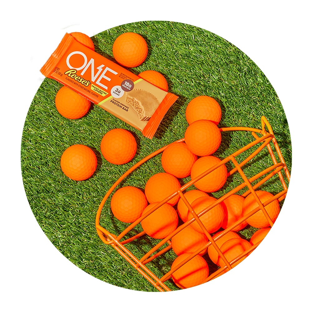 one reeses peanut butter lovers flavored protein bar beside of basket of golf balls