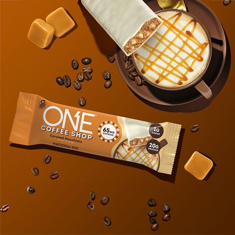 one coffee shop caramel macchiato flavored protein bar beside coffee beans and beverage